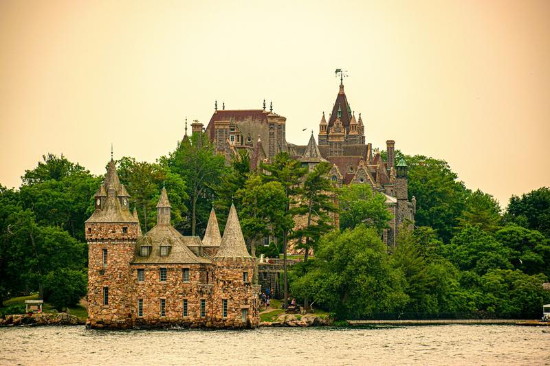 Boldt Castle rising above the trees on Heart Island, with the stone power house at the water