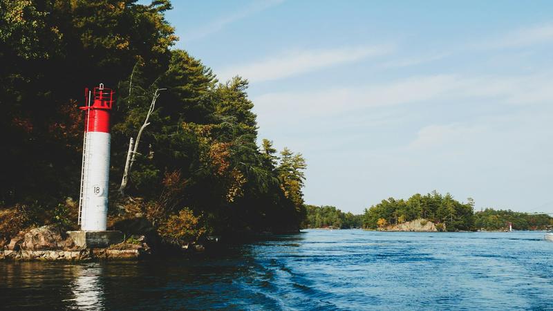 A channel light on a rocky island shore with more islands across the water
