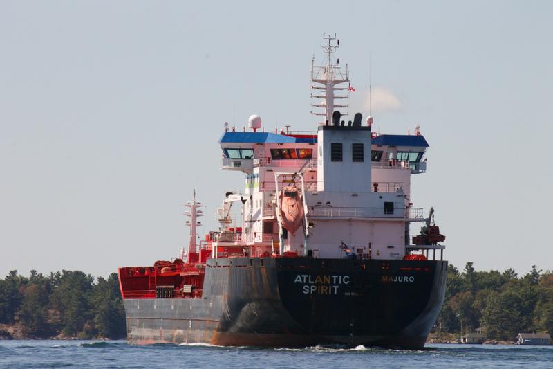 A freighter heading down the St. Lawrence River past wooded shores