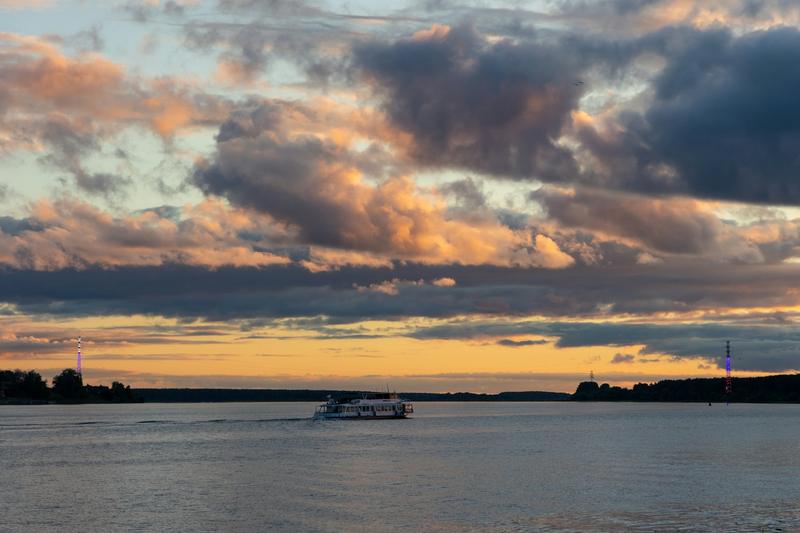 A colorful sunset sky over the water with a boat in the distance