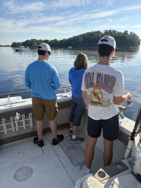 Three young anglers fishing off the back of the boat near the islands