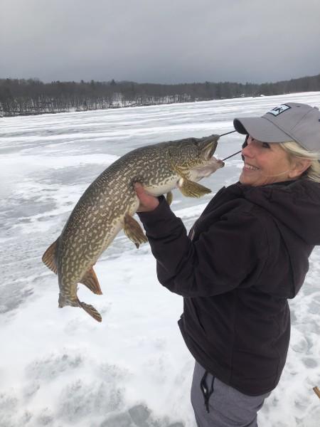 Angler on the frozen river kissing a big northern pike