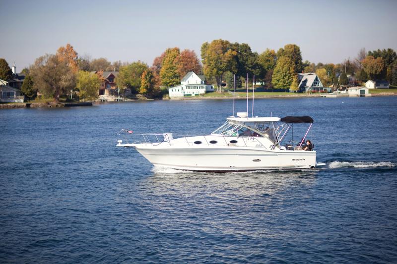 A fishing boat cruising past island cottages on the St. Lawrence River in fall