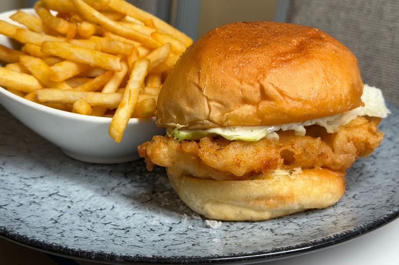 Crispy fried fish sandwich with lettuce on a toasted bun, with fries on the side